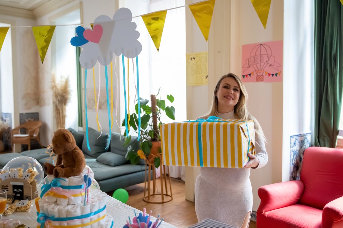 An expectant parent opening a gift at a baby shower